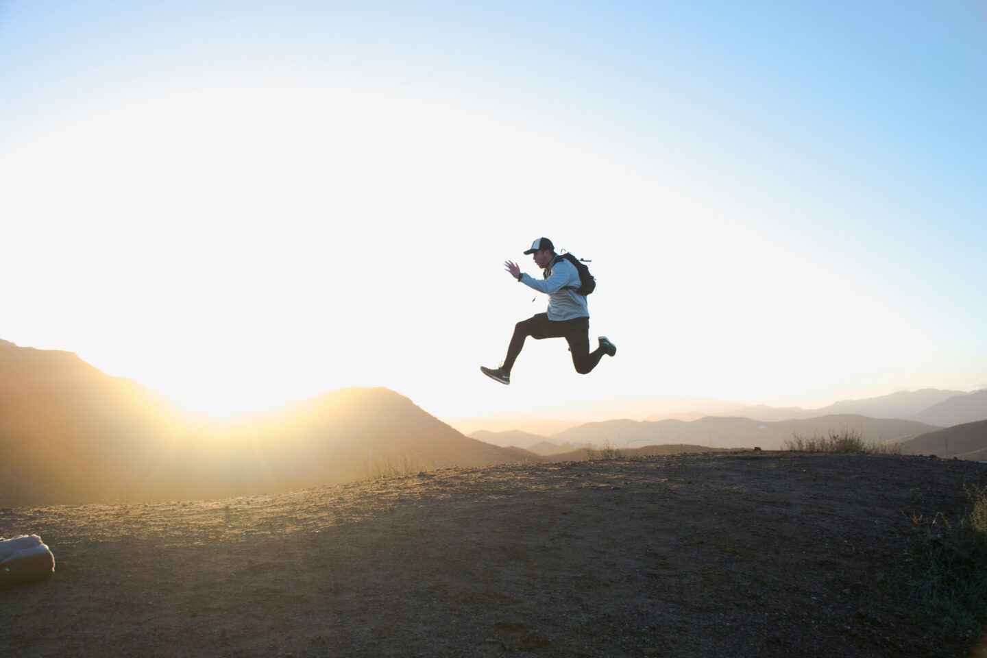 A person leaping mid-air across a mountain ridge at sunrise, symbolizing the courageous leap toward healing, freedom from rigid protective roles, and the empowerment found through IFS therapy.