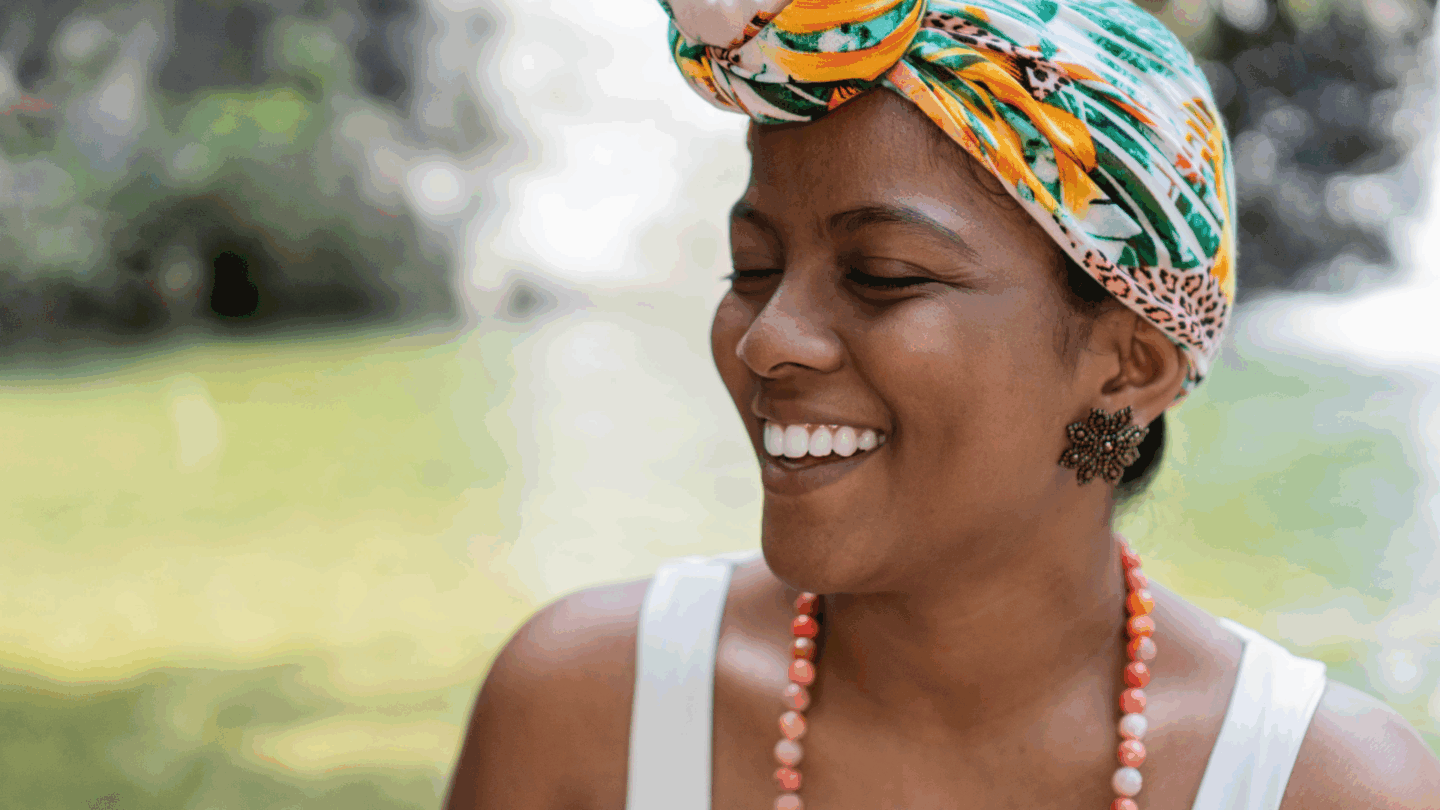 Woman smiles with her eyes closed outside. Begin your trauma healing journey today at Kindful Body in Orange County, CA. We also offer online eating disorder treatment at Kindful Body—please contact us for details.